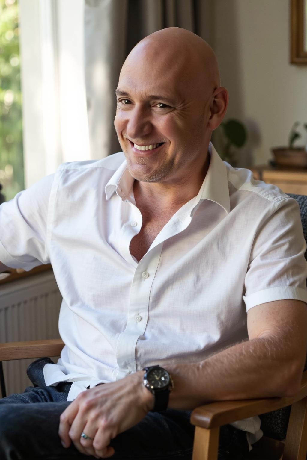 Ivan Demers, co-founder of Alchemize Your Life After 50, smiling in a white shirt, seated by a window